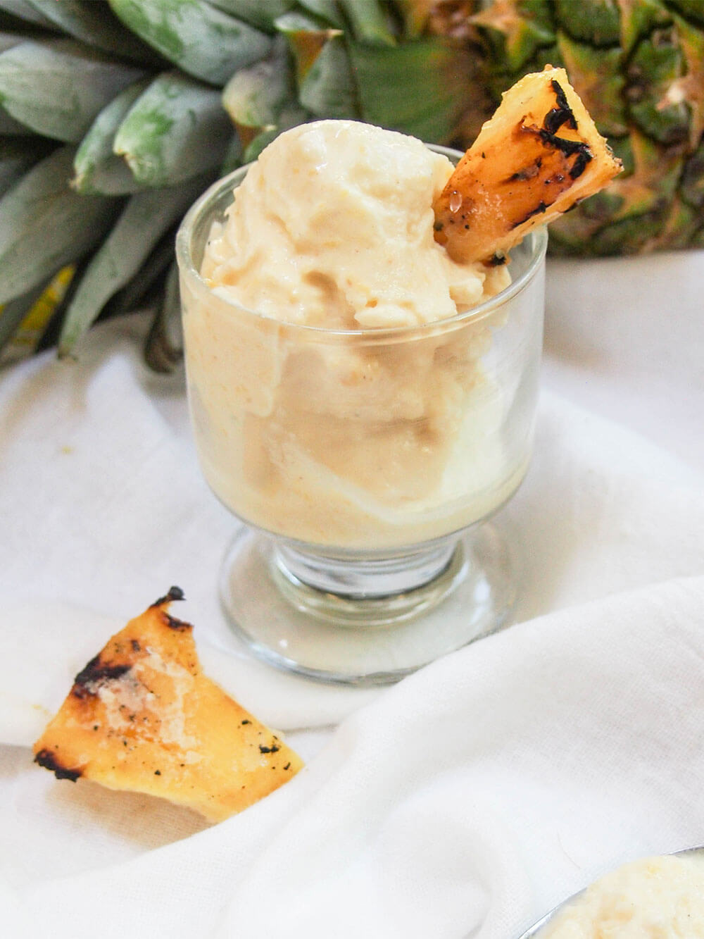grilled pineapple ice cream in glass with pineapple behind
