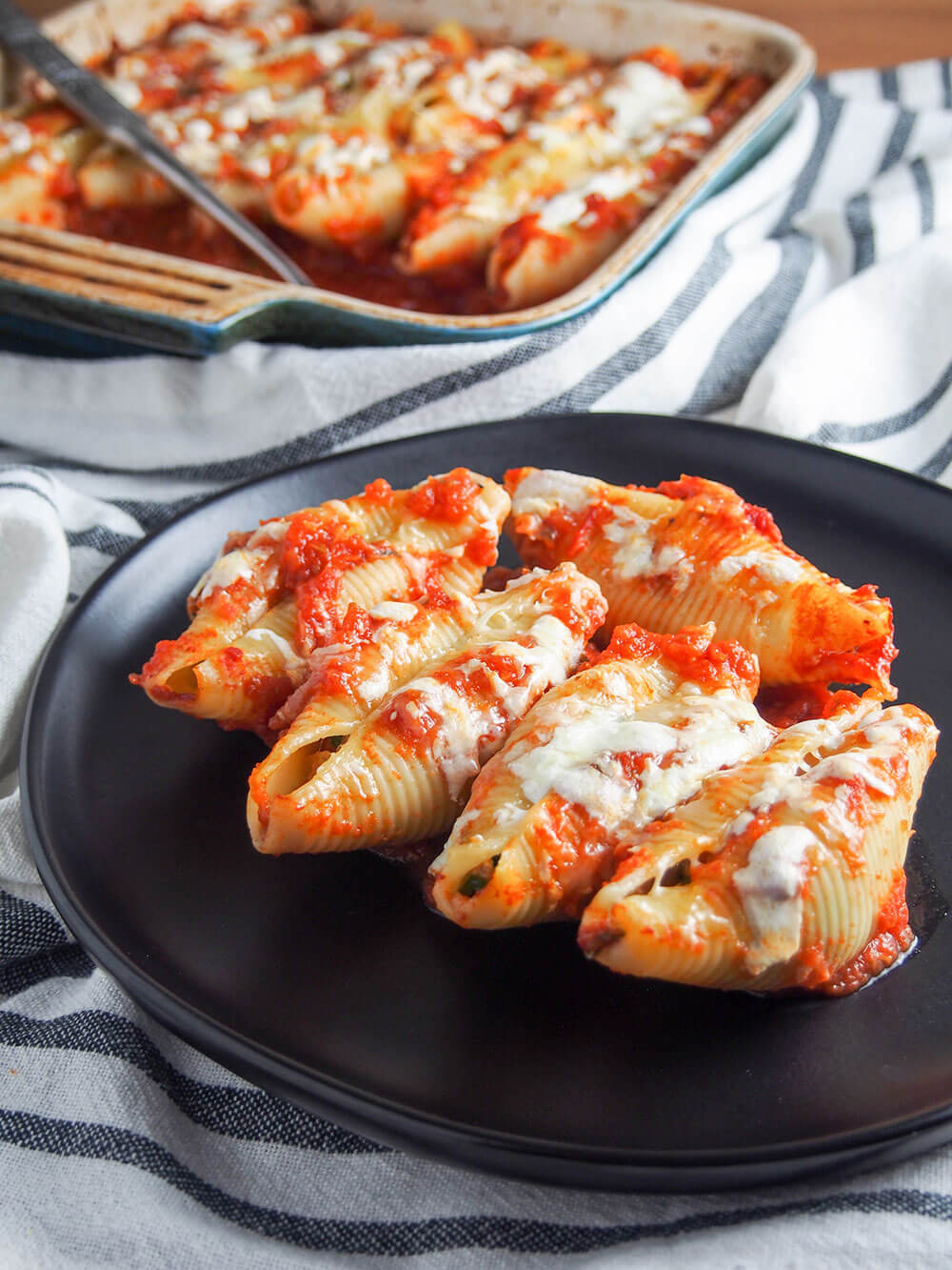 pulled pork stuffed shells on plate with baking dish with rest behind