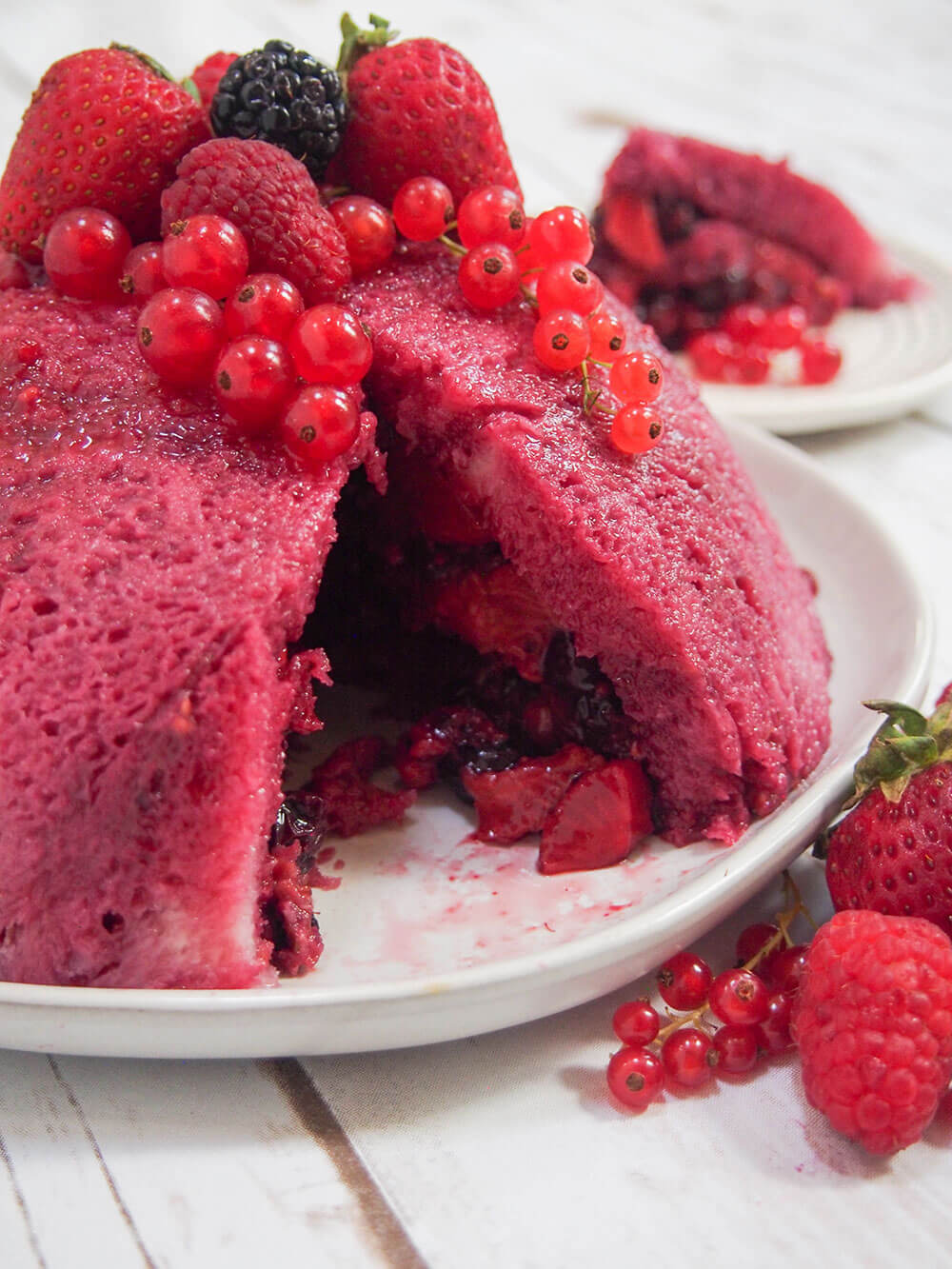 summer pudding on plate with slice taken out so you can see berries inside