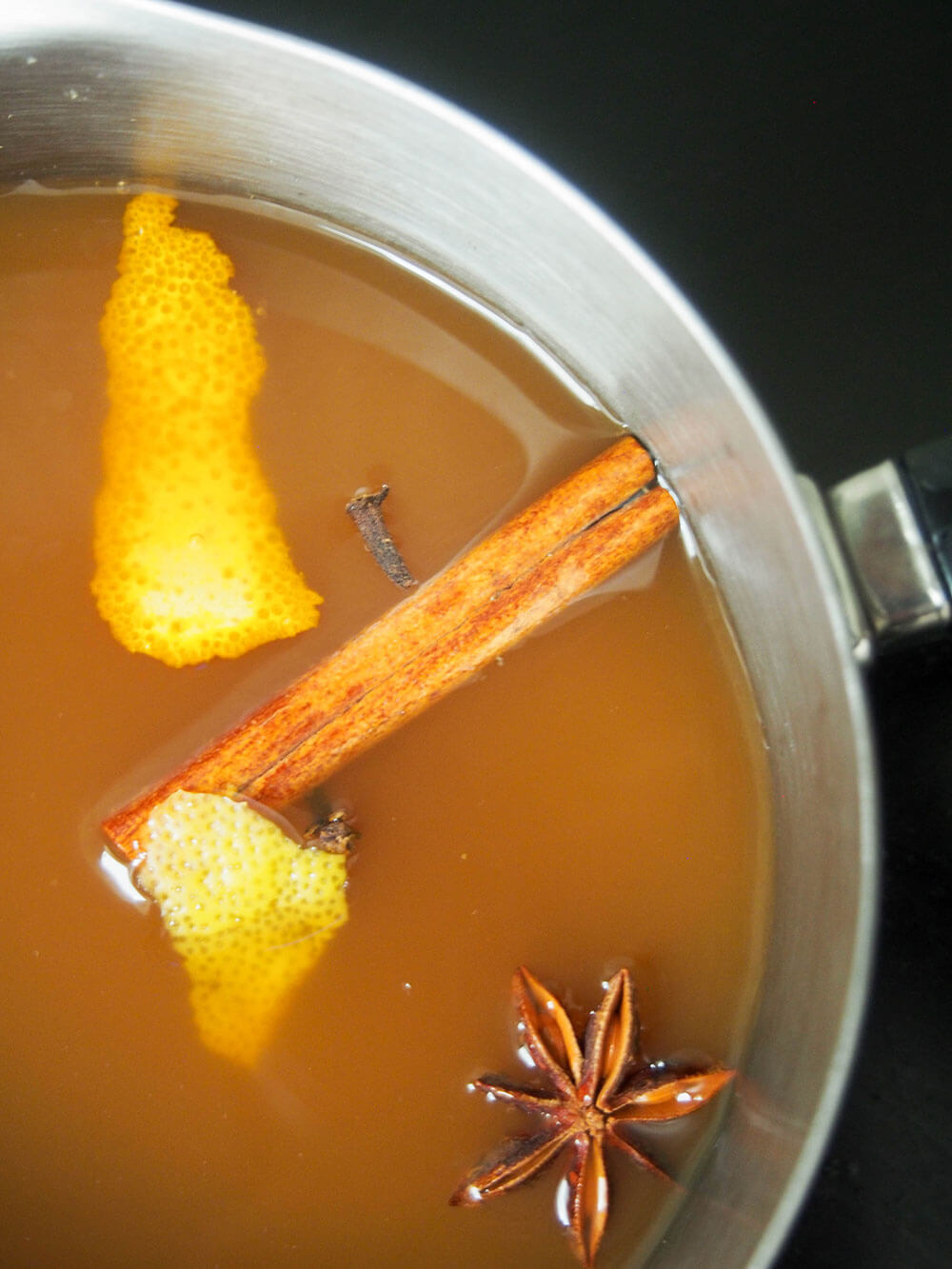 warming apple cider in pan with spices