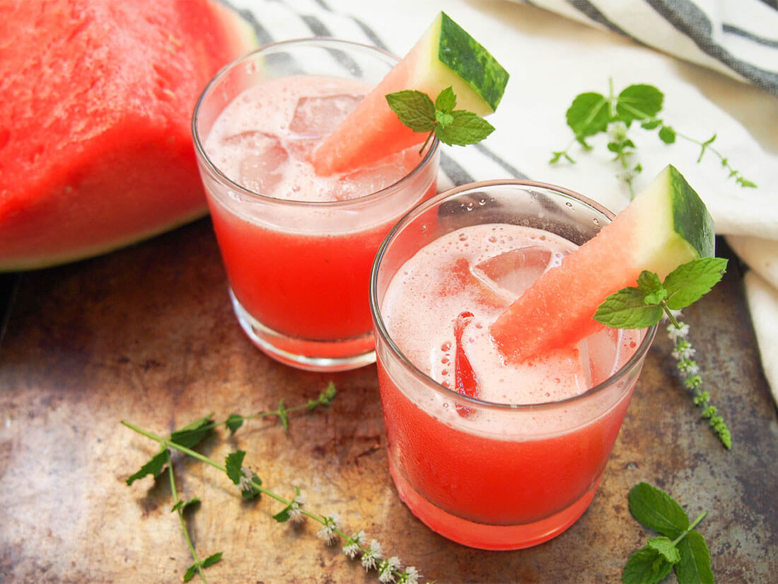 glasses of watermelon coconut agua fresca with watermelon chunk to side