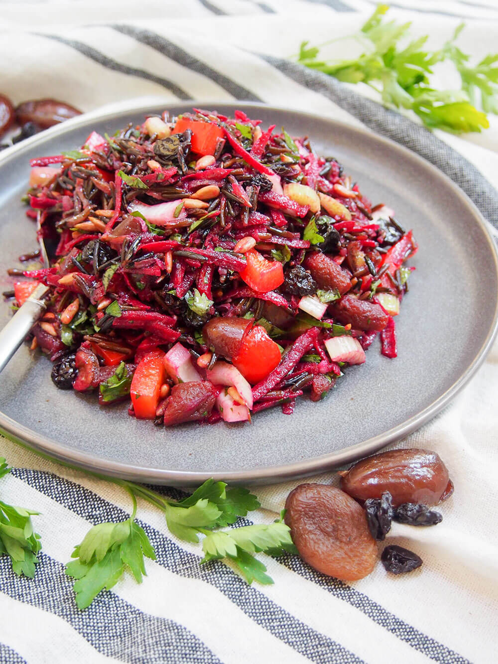 This wild rice salad is a wonderful combination of textures and flavors. A little tart from the vinaigrette, sweet from the dried fruit, with crunchy veg and tender fruit. And a whole lot of wholesome tastiness. wild rice salad on plate with spoon to the side