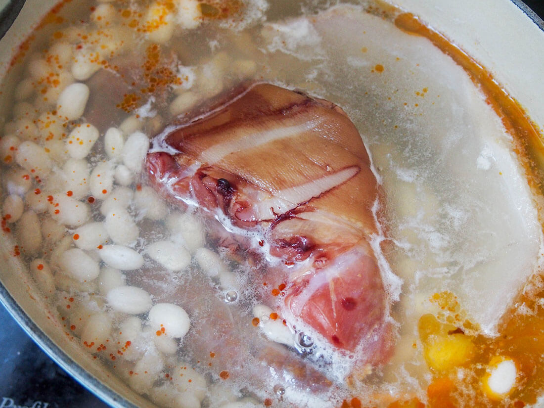 early stages cooking Fabada Asturiana with ham hock and chorizo in pot with beans and water
