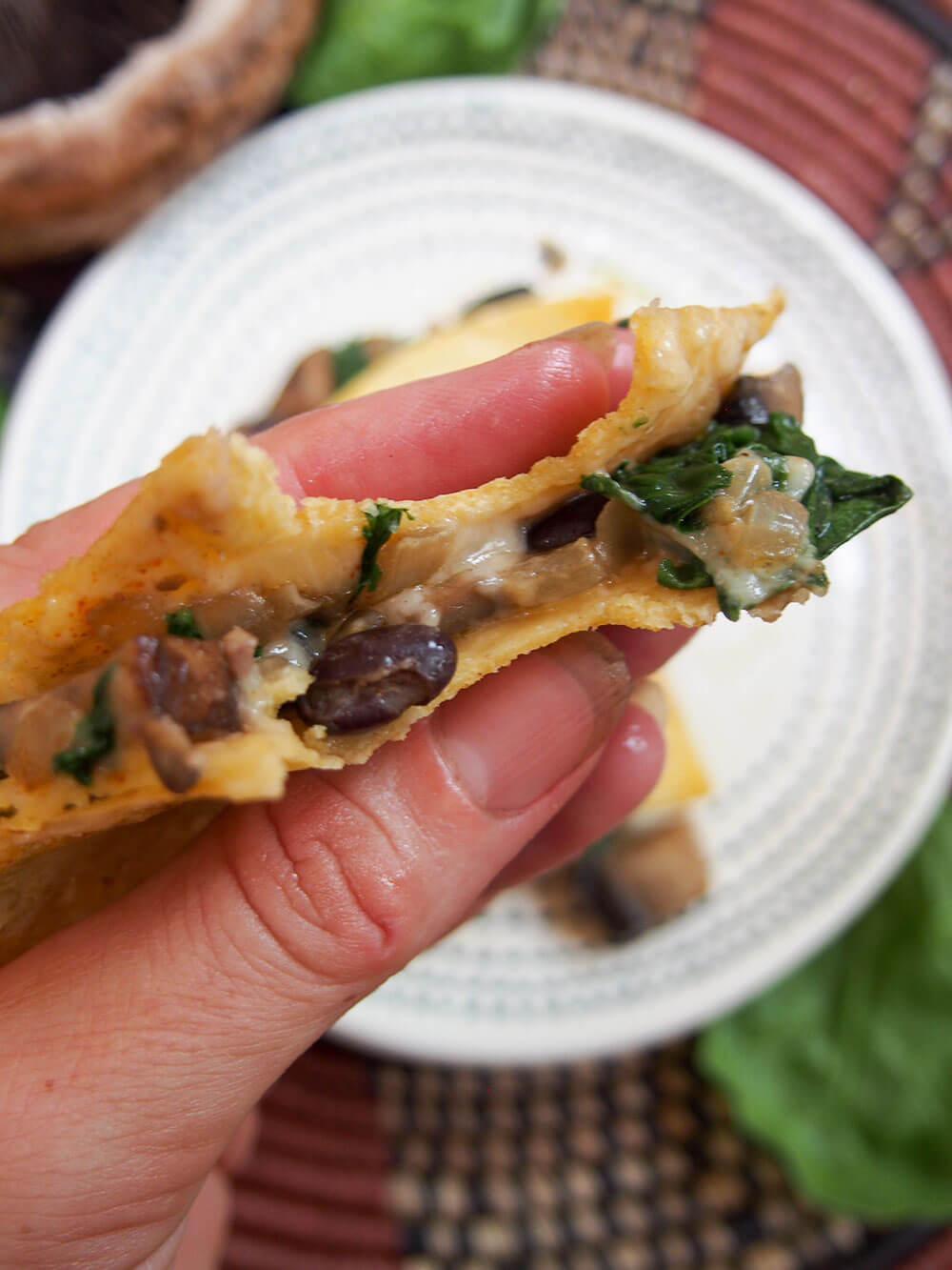mushroom quesadillas held in hand with bite taken out