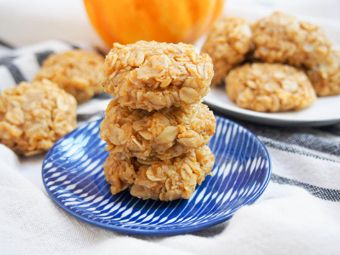stack of pumpkin cookies on small plate with more cookies behind