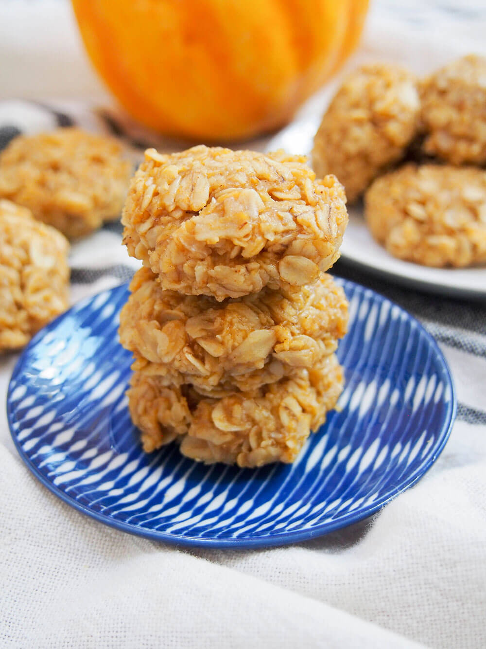stack of three no bake pumpkin cookies on small plate with more behind