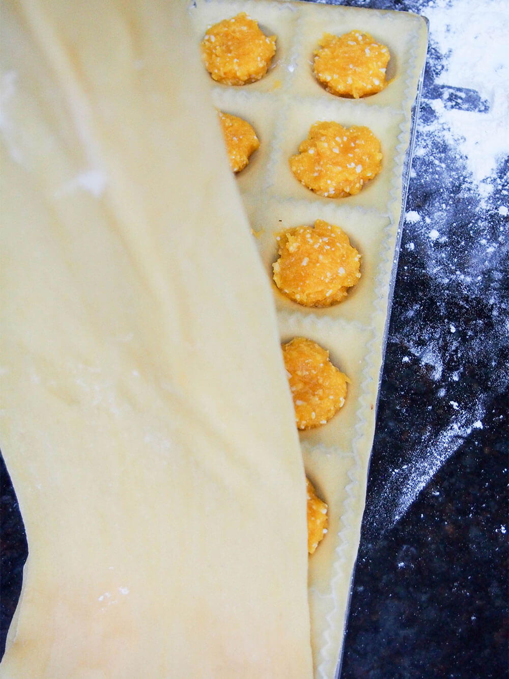 putting top layer of pasta over pumpkin filling on lower layer of pasta in mould