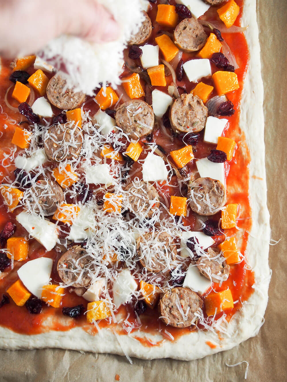 adding cheese on top of other pizza toppings