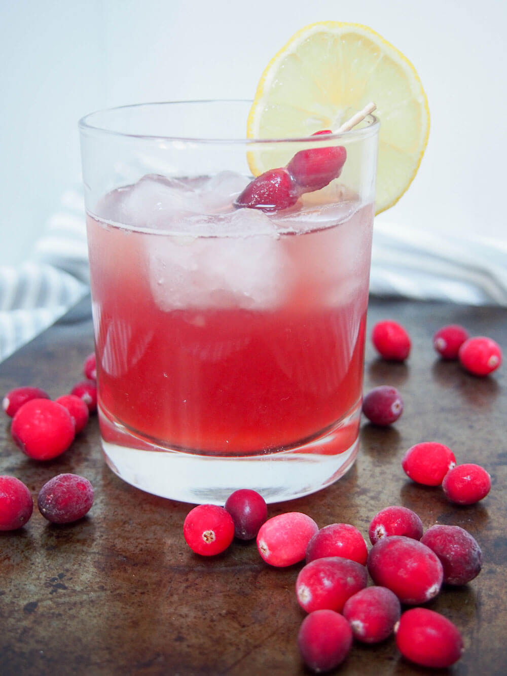 glass of cranberry whiskey sour from side with cranberries in front