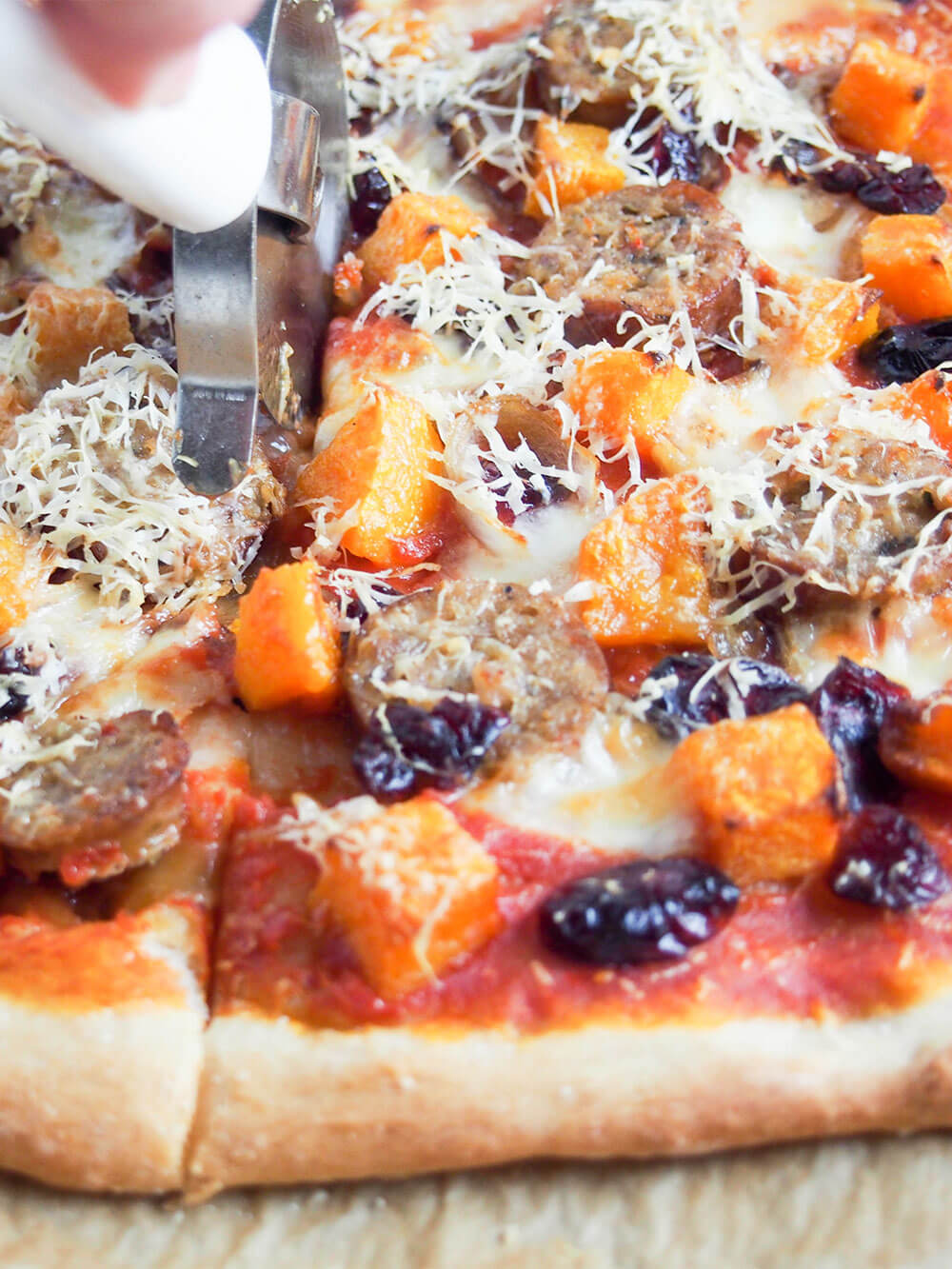 cutting fall pizza with sausage and squash