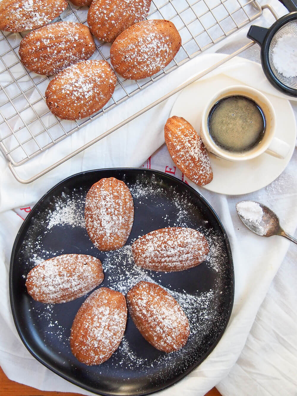 gingerbread madeleines on plate, on cooling rack and cup of coffee to side
