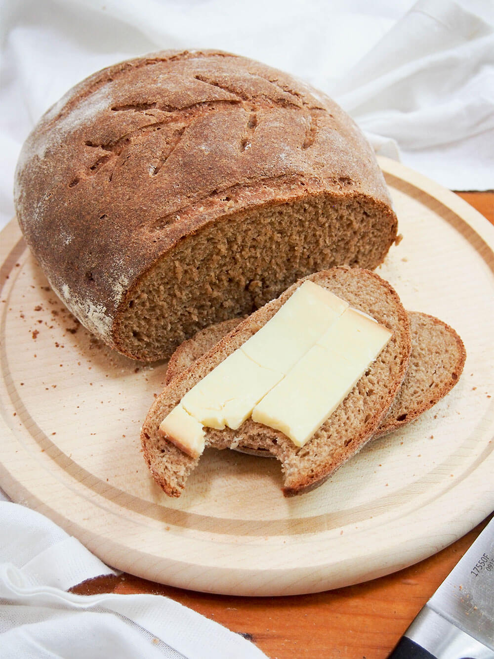 sourdough rye bread with a slice topped with cheese in front of rest of loaf