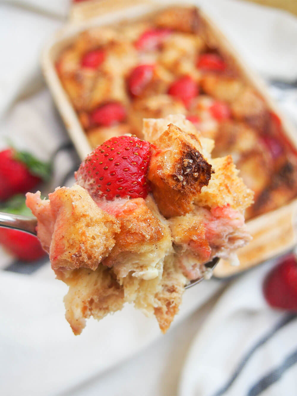 spoonful of strawberry French toast bake held in front of dish