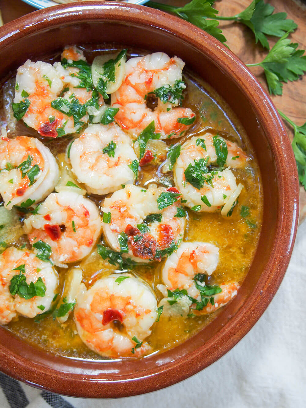 Gambas al ajillo (Spanish garlic shrimp) in red ceramic dish viewed from omverhead
