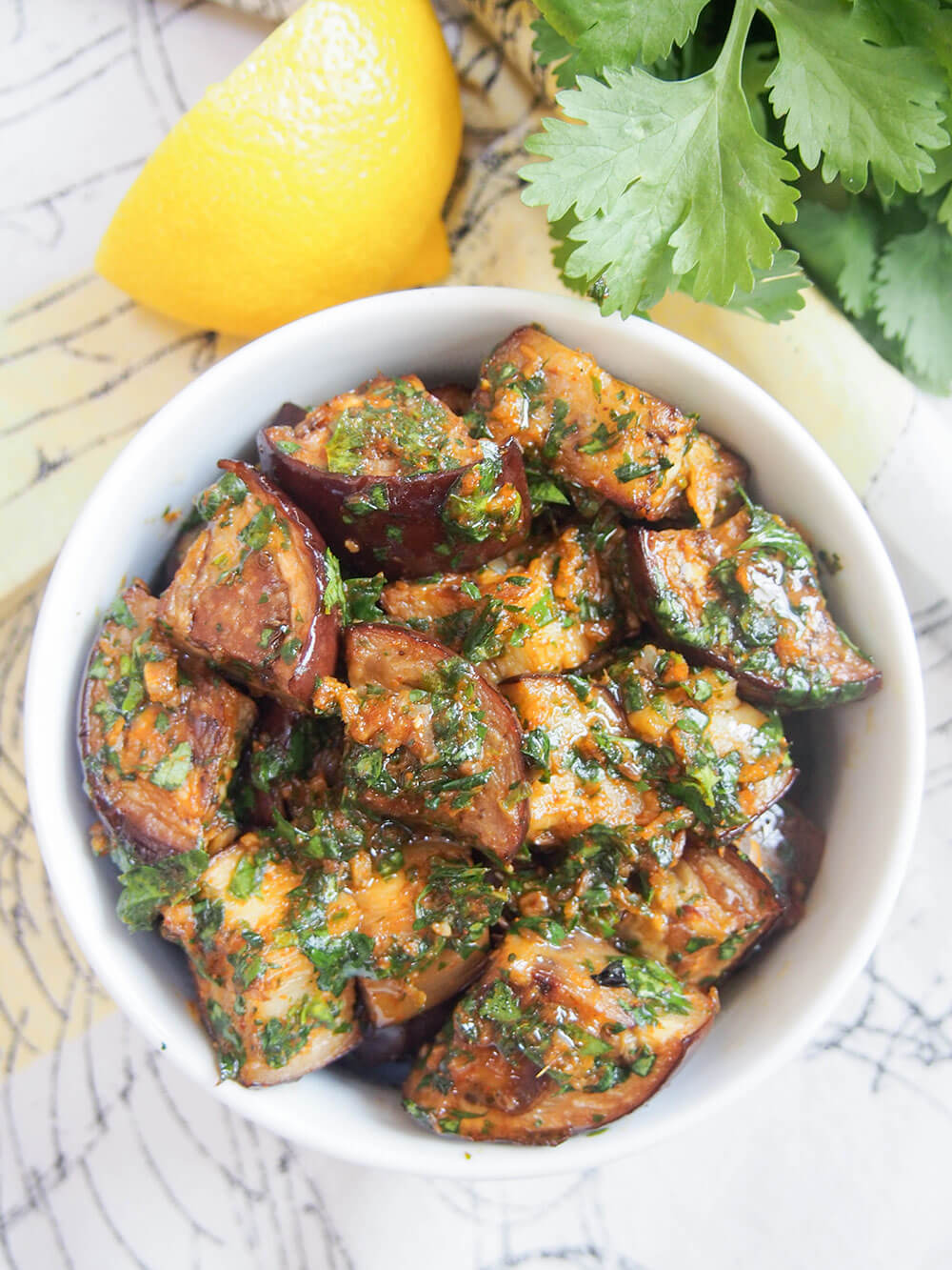 bowl of Moroccan eggplant with chermoula from overhead with lemon and cilantro above