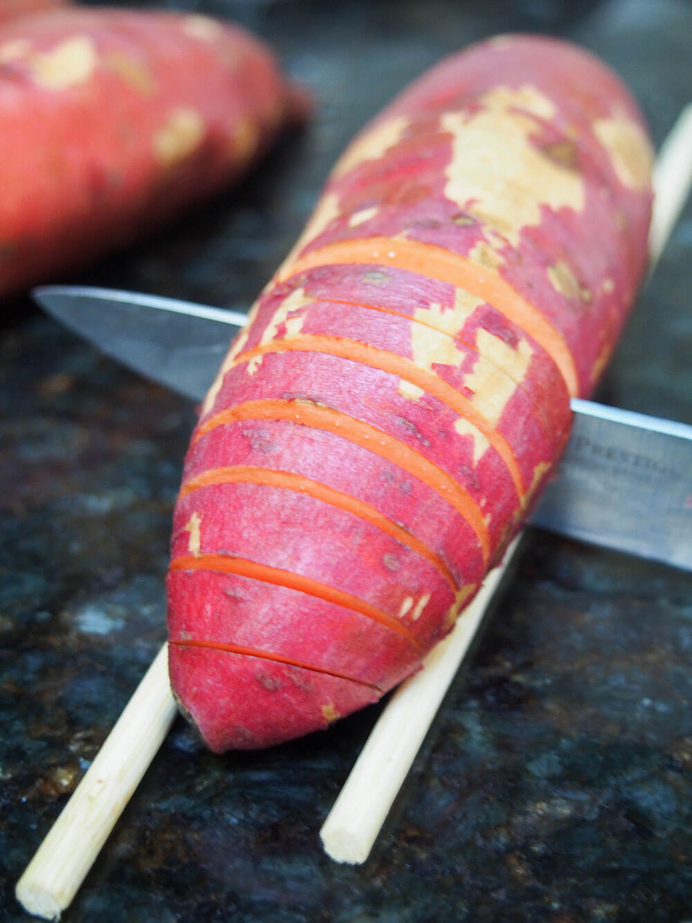 cutting hasselback sweet potatoes using chopsticks as rest