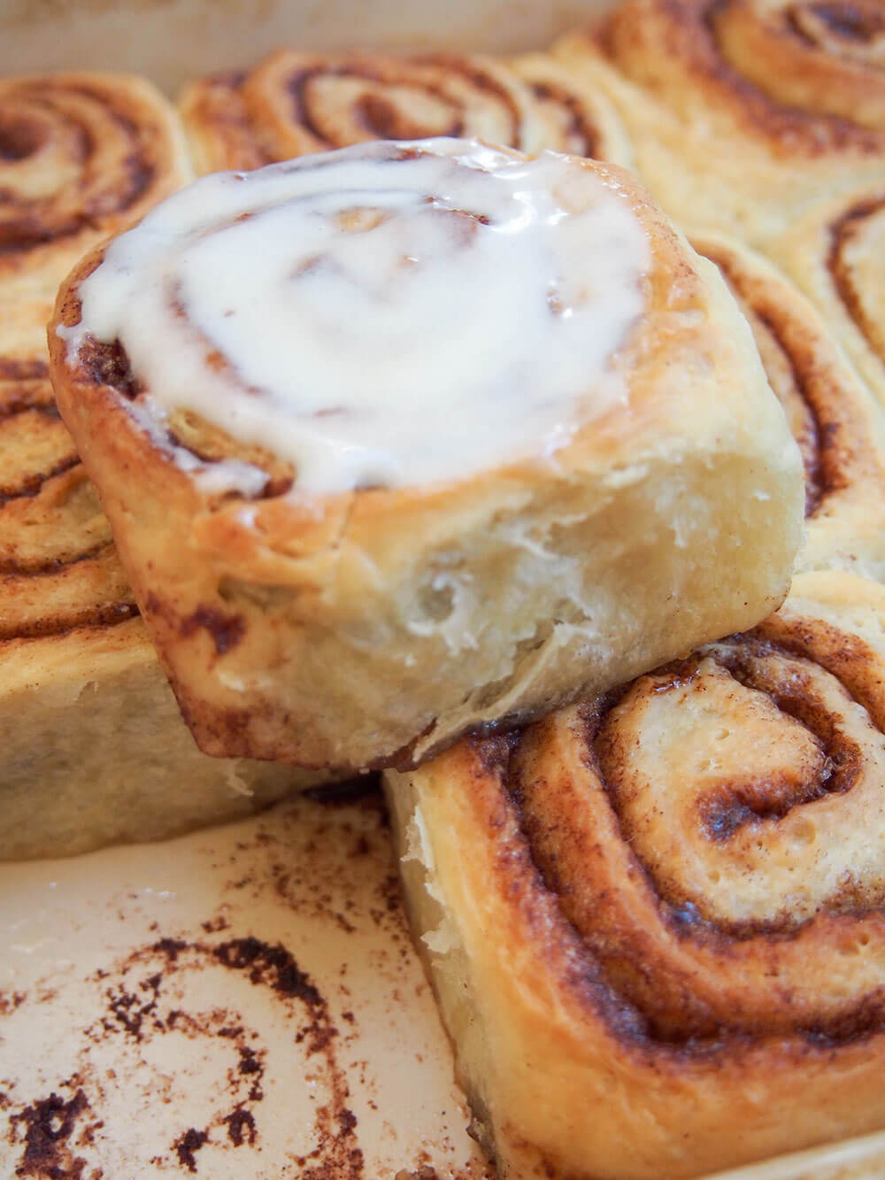 eggnog cinnamon rolls with one topped with frosting perched on top of others