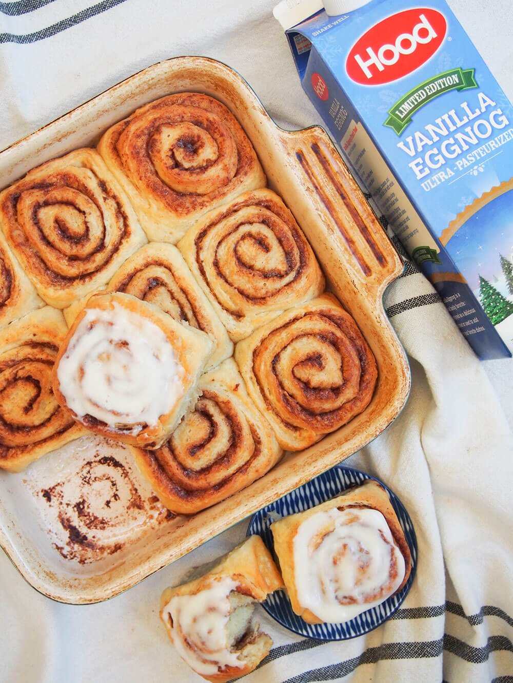 dish of eggnog cinnamon rolls with carton of eggnog to side