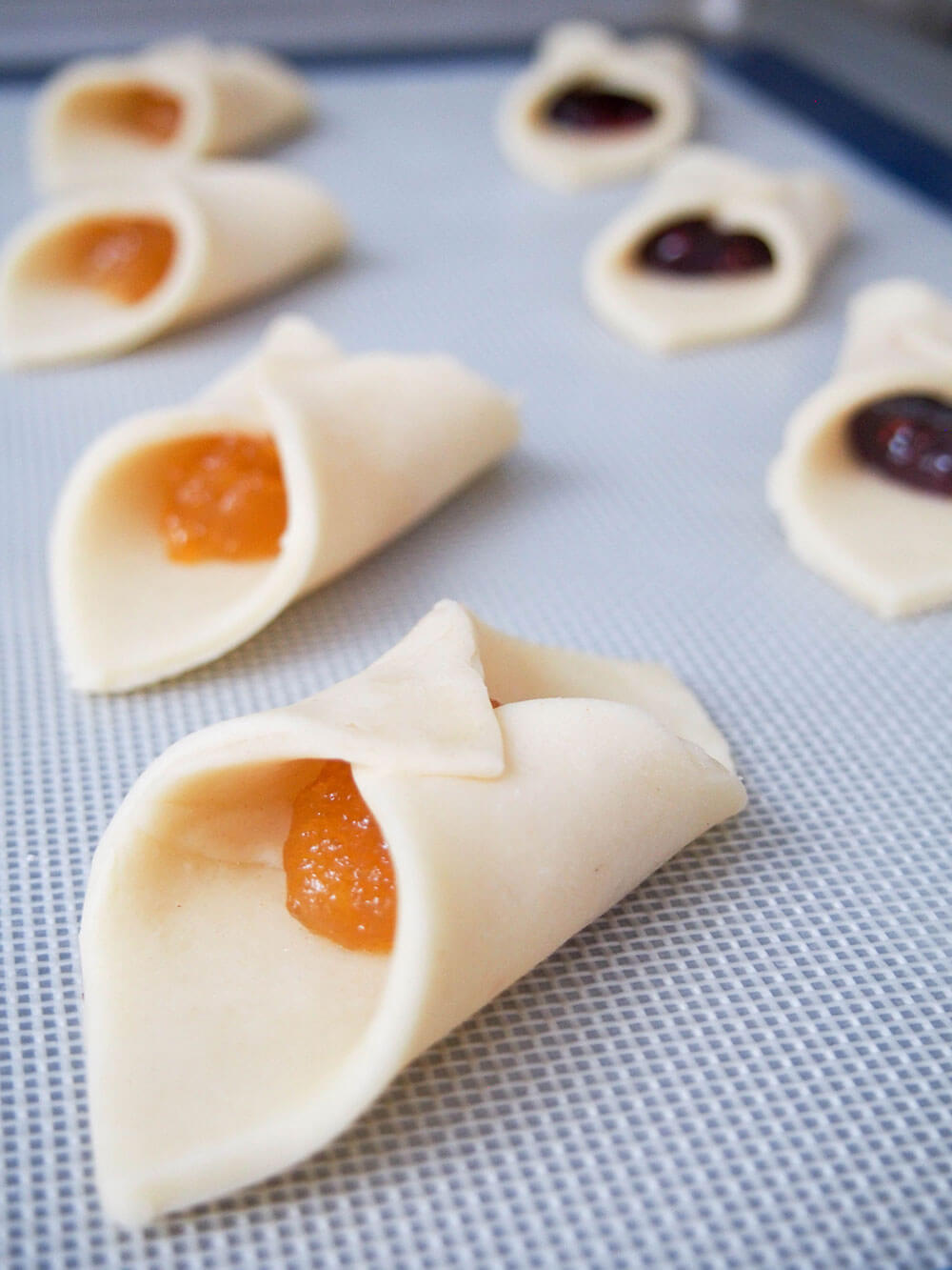 folded over cookie dough with filling inside on baking sheet ready to bake