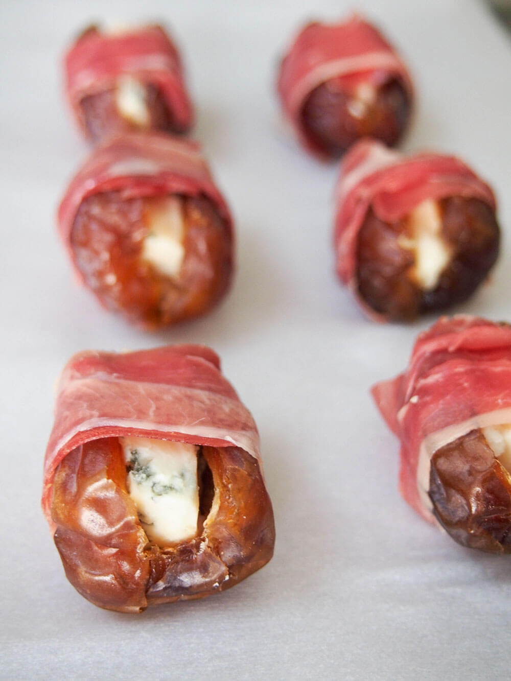 prosciutto wrapped dates with cheese in middle wrapped ready to bake