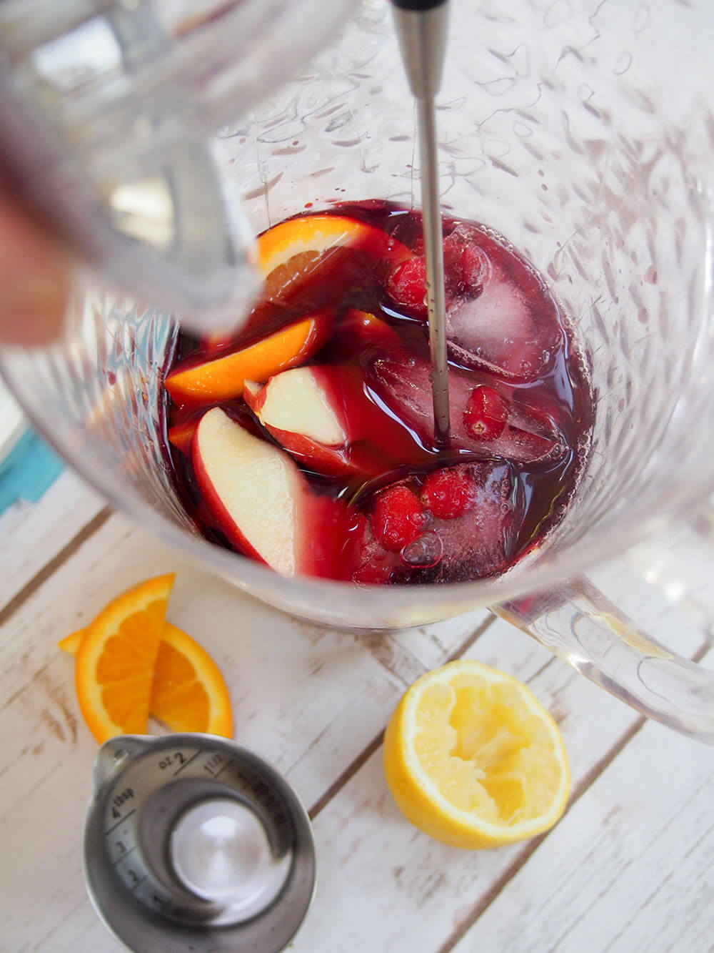 mixing cranberry sangria in jug
