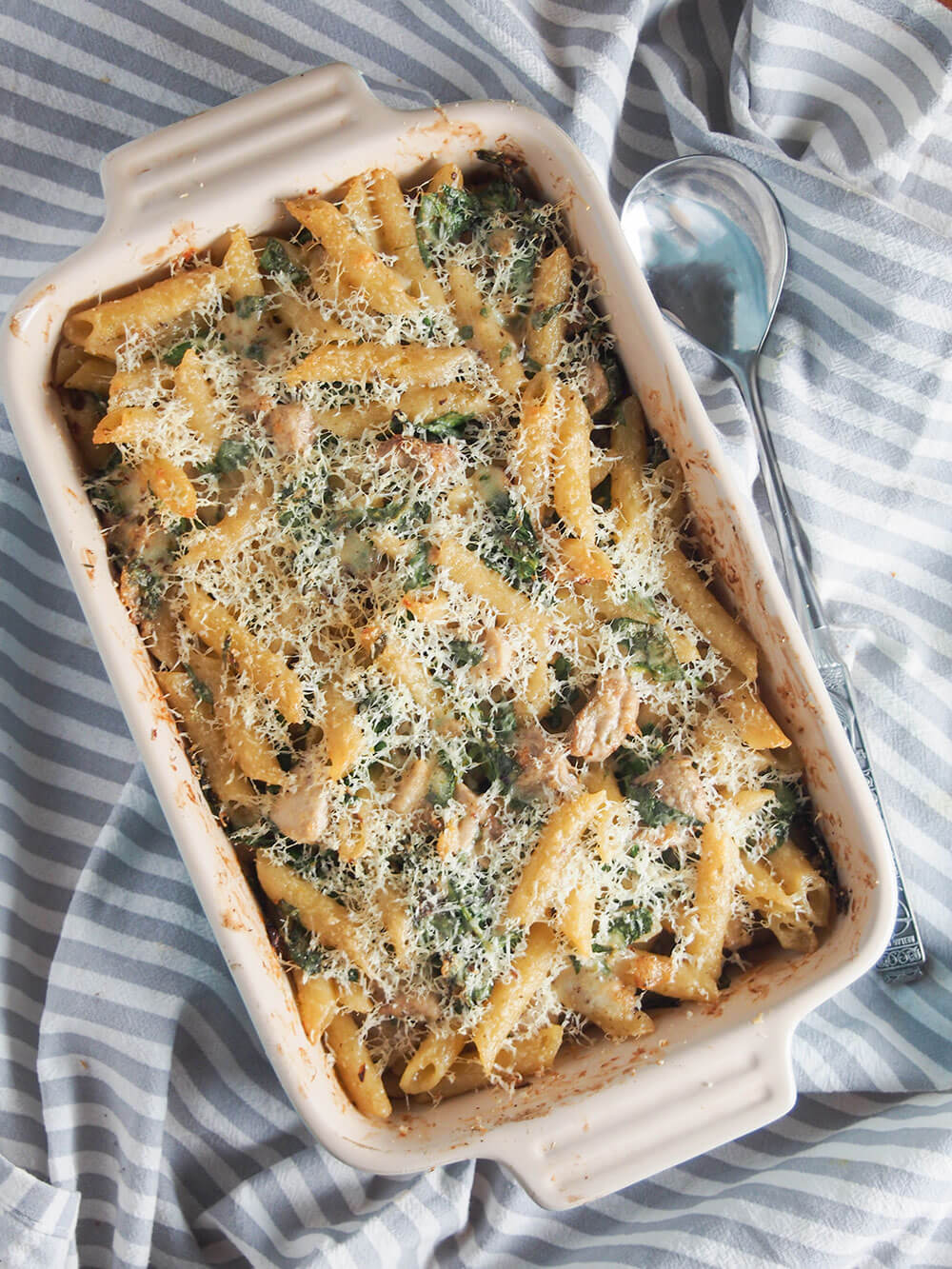 This creamy lemon chicken pasta bake has so much tastiness going on from the tarragon lemon cream sauce that wraps together the pasta, chicken and spinach. Creamy lemon chicken pasta bake in dish with spoon to side of baking dish