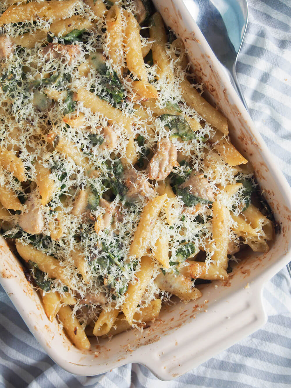 This creamy lemon chicken pasta bake has so much tastiness going on from the tarragon lemon cream sauce that wraps together the pasta, chicken and spinach. Creamy lemon chicken pasta bake in dish, part view, from overhead
