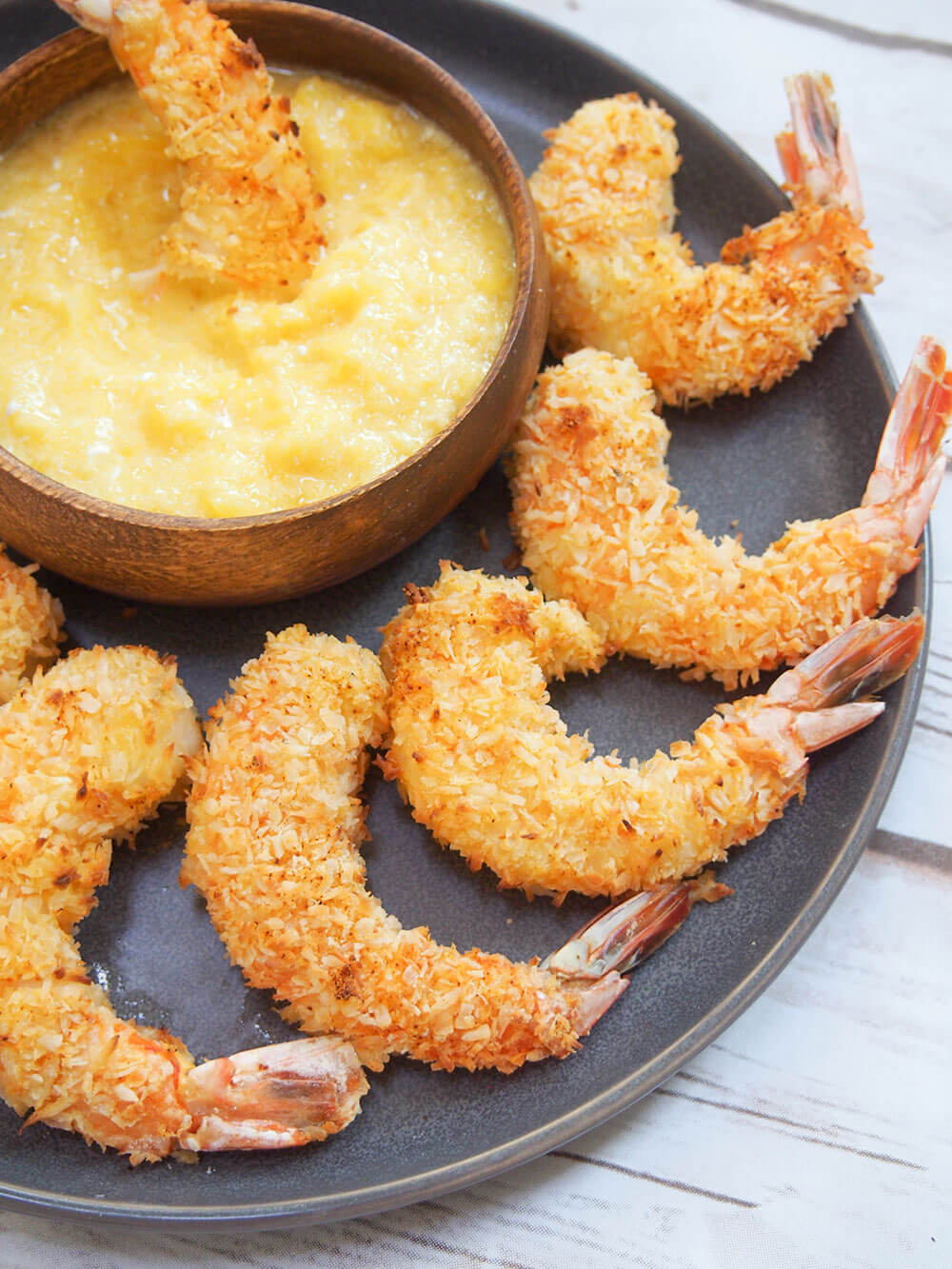  plate of baked coconut shrimp with mango dipping sauce with a shrimp in the sauce