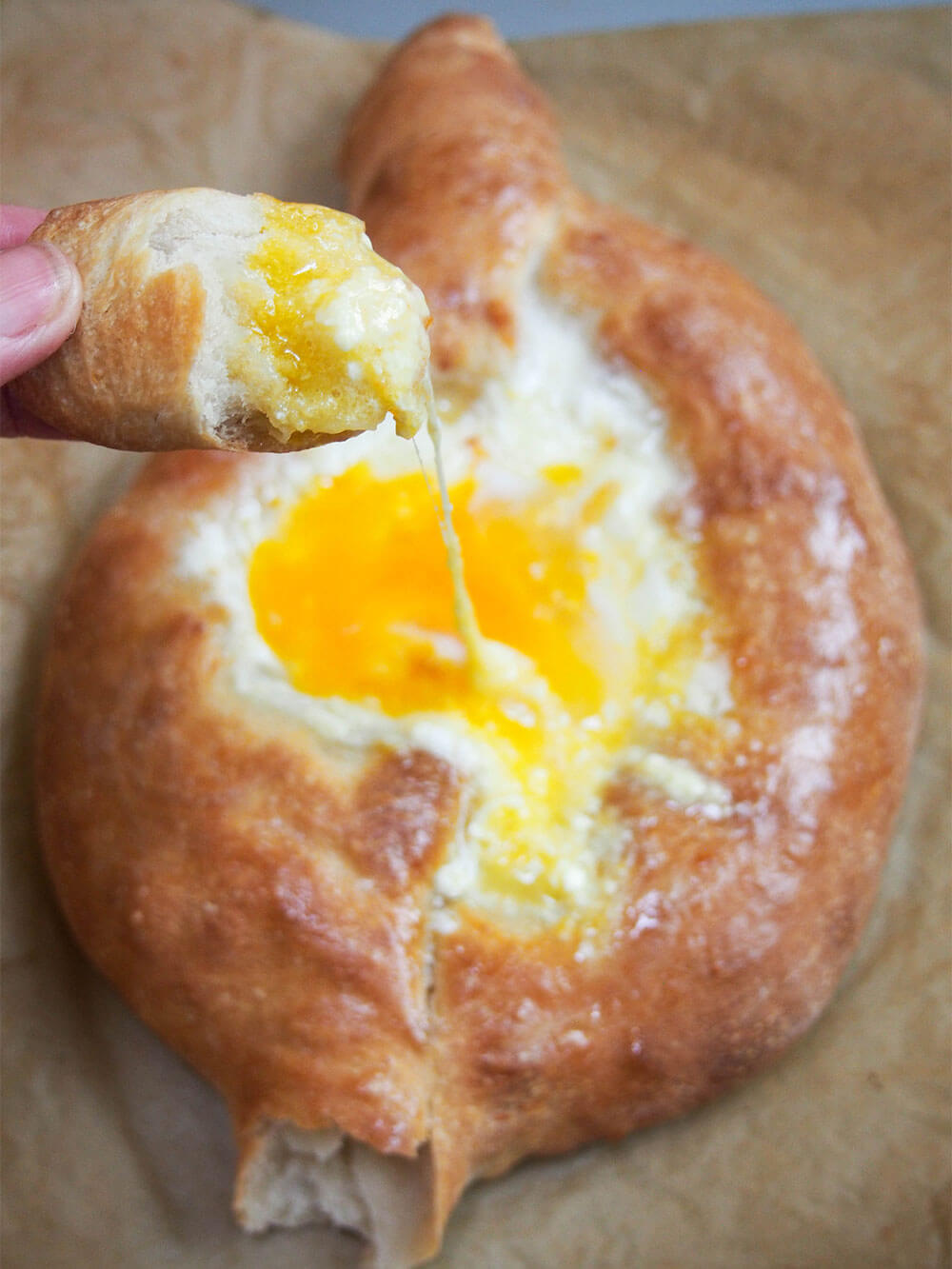 Adjaruli khachapuri Georgian cheese bread torn and dippied into the egg and cheese filling