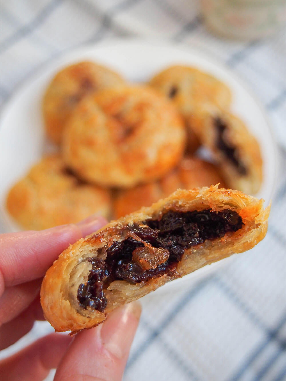 Eccles cakes - crisp currant filled pastries bitten-into Eccles cake held in hand showing filling inside