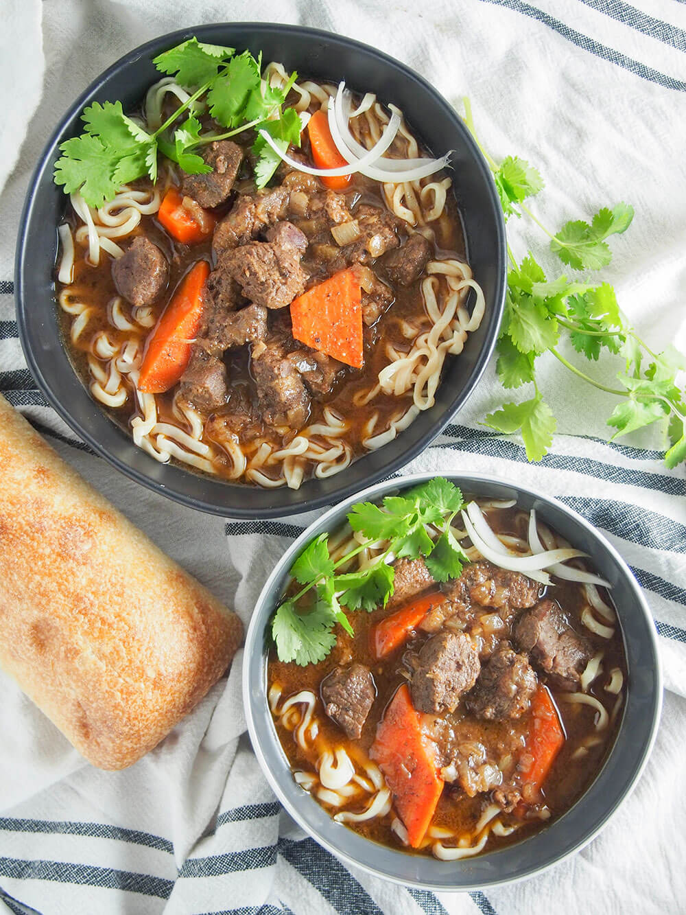 Bo kho may not be as well known as pho, but it's a classic dish you need to get to know. This Vietnamese beef stew has a wonderful depth of flavor from aromatic spices, lemongrass, ginger and coconut water. It's warming, delicious and easy to make too. two bowls of bo kho Vietnamese beef stew viewed from overhead