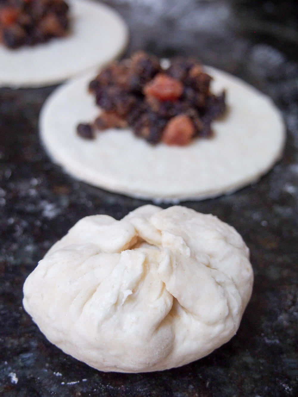 filling and forming Eccles cakes rounds of pastry with topping on behind and one bunched together to seal to front