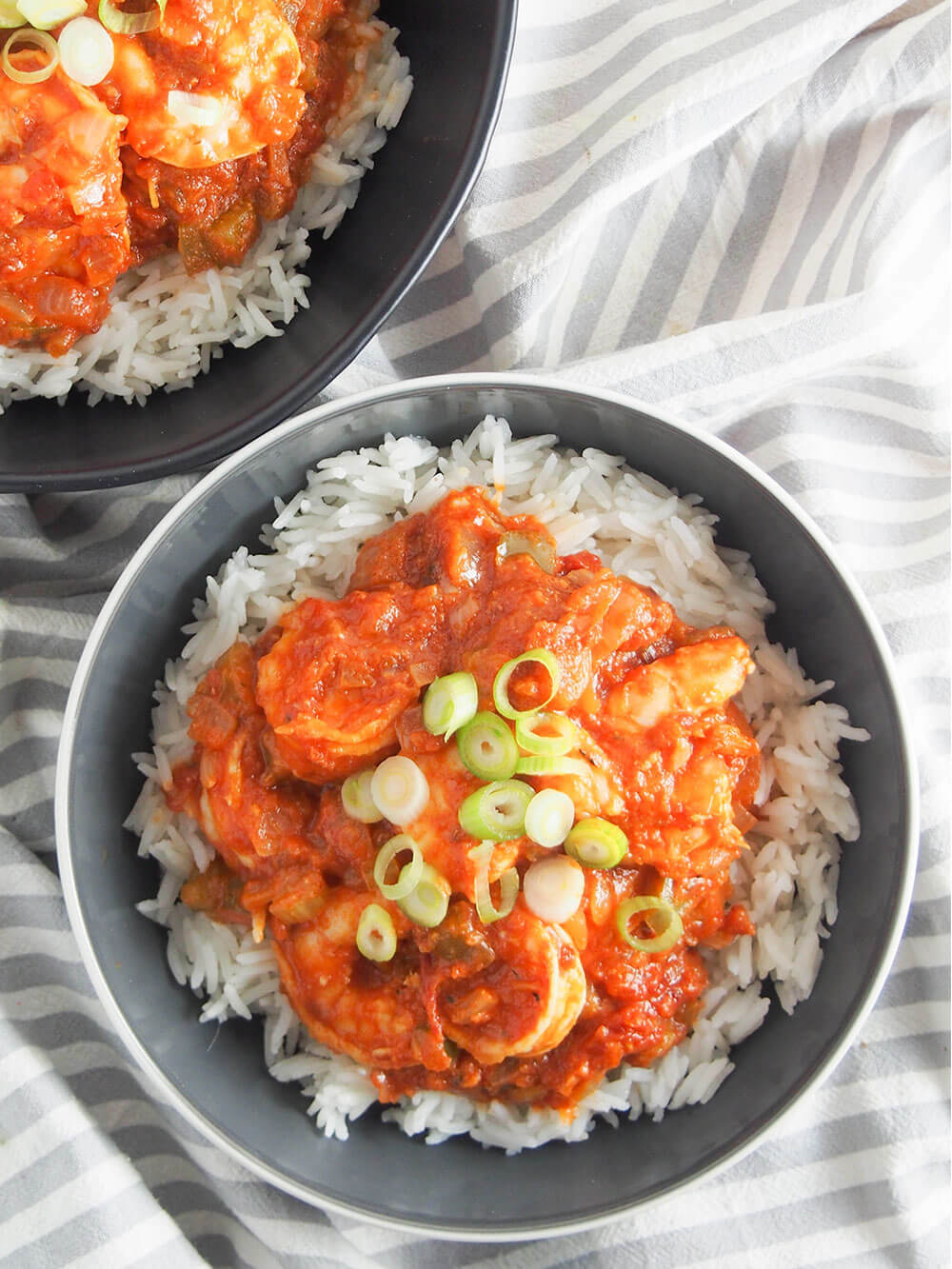 bowl of shrimp creole over rice with corner of another bowl above