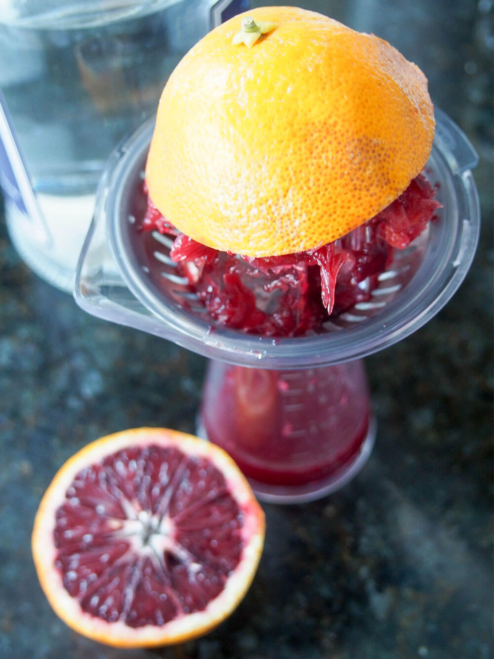 squeezing juice from blood orange with juicer