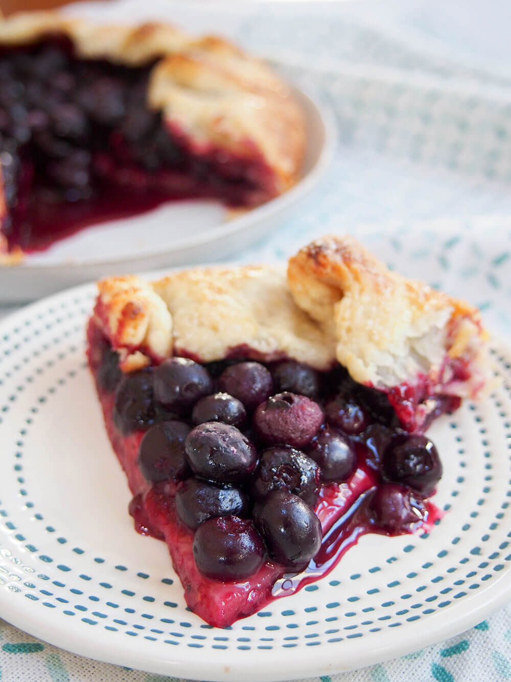 slice of blueberry galette on small plate with berries oozing out