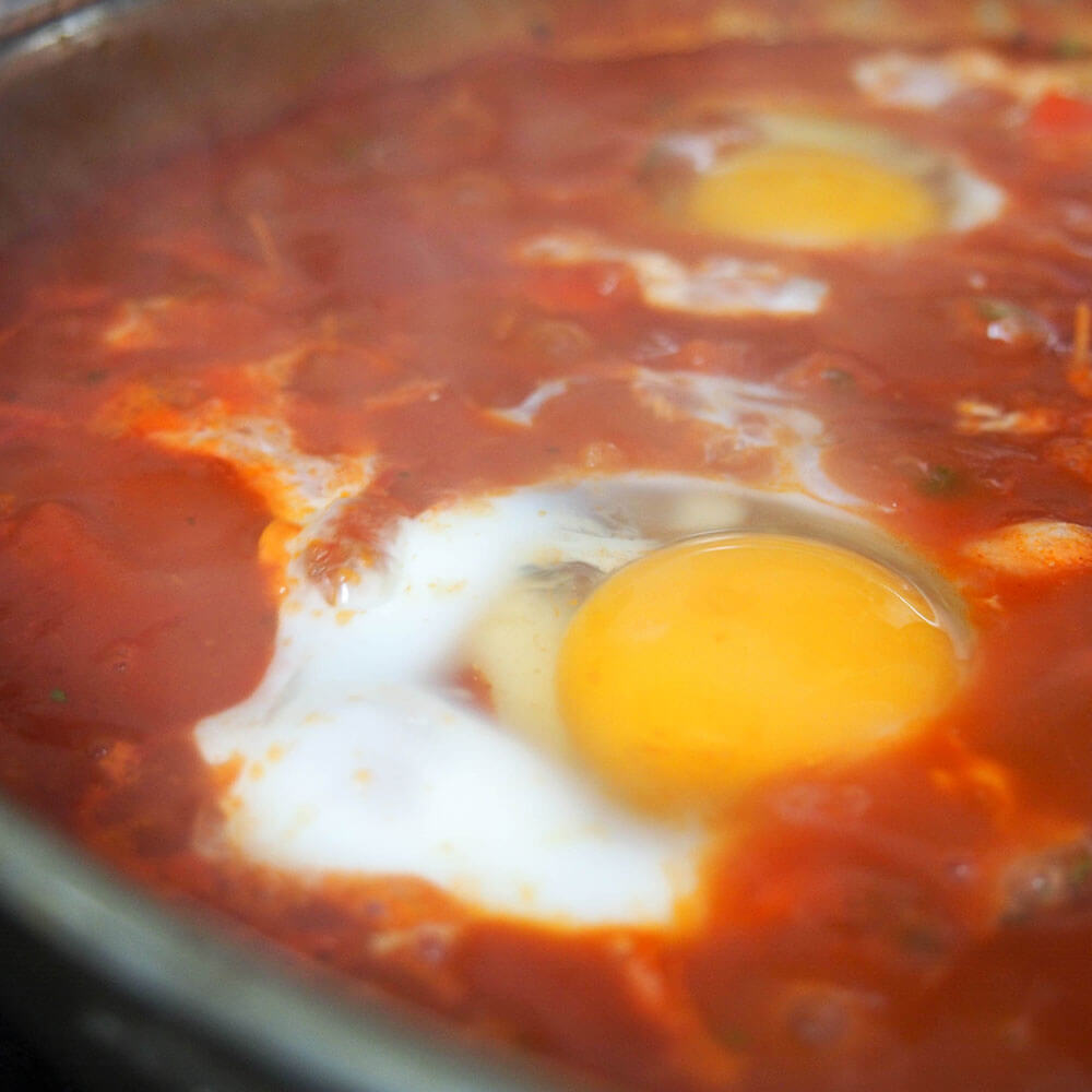 cooking egg in shakshuka for shakshuka hummus