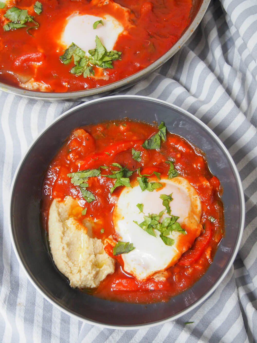 bowl of shakshuka hummus with part of another bowl in top