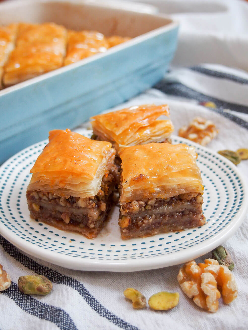 baklava pieces sitting on a plate in front of dish with rest of baklava