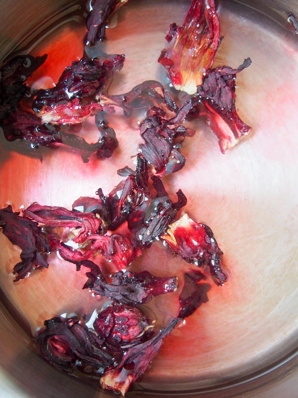hibiscus flowers in water with some color seeping from them