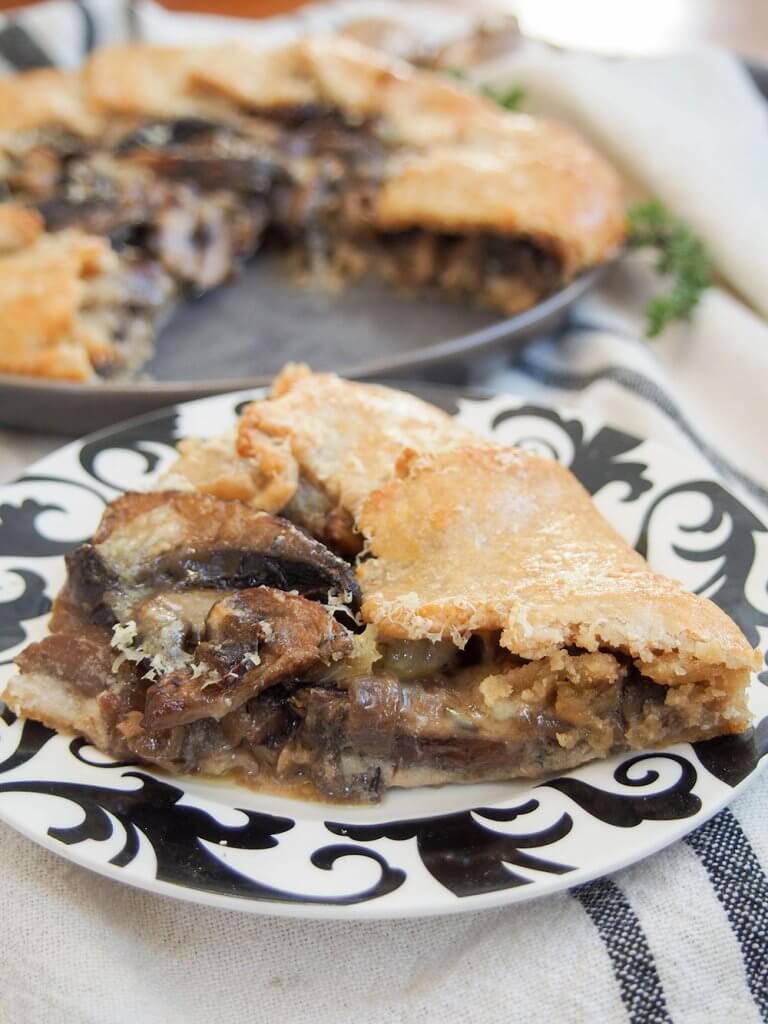 mushroom galette slice on small plate with rest of galette behind