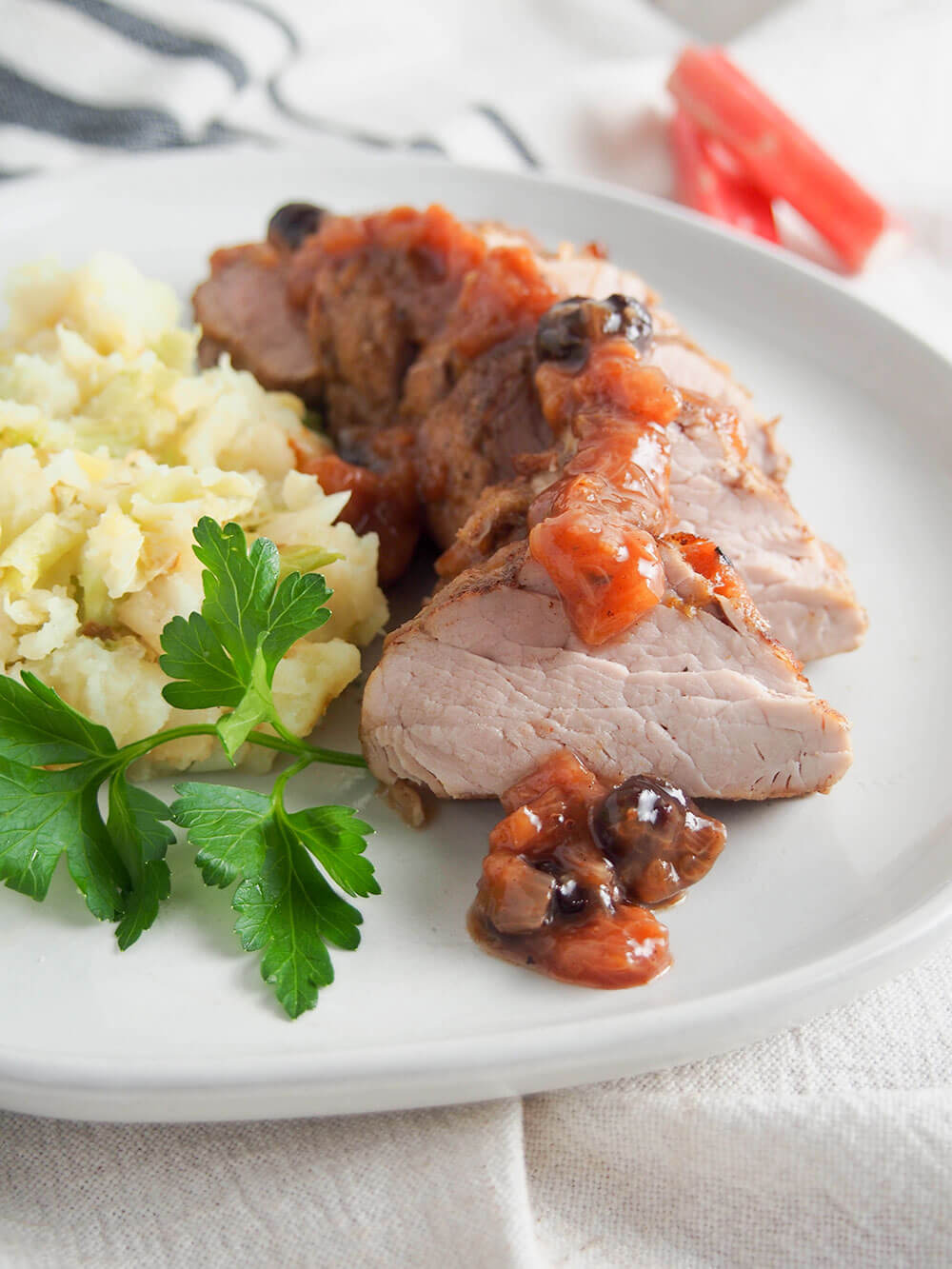 pork tenderloin with rhubarb chutney over top and parsley garnish to side