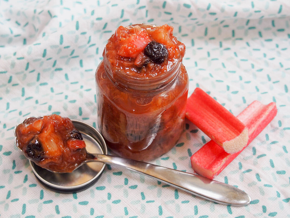 Rhubarb chutney in jar with some on a spoon to the side