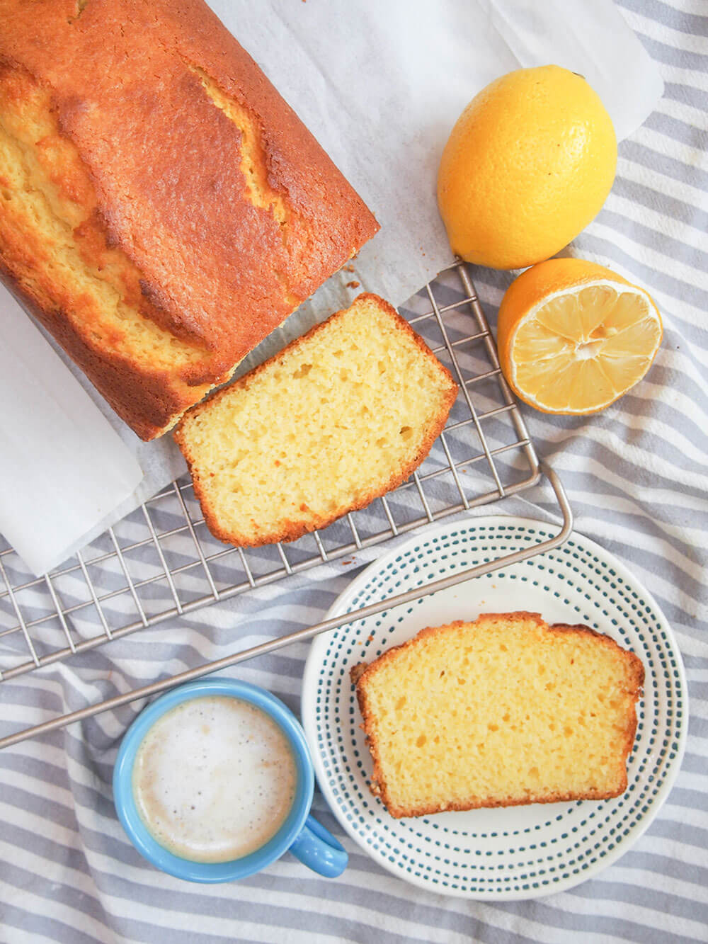French lemon yogurt cake with slice on plate and coffee on the side, lemon next to loaf
