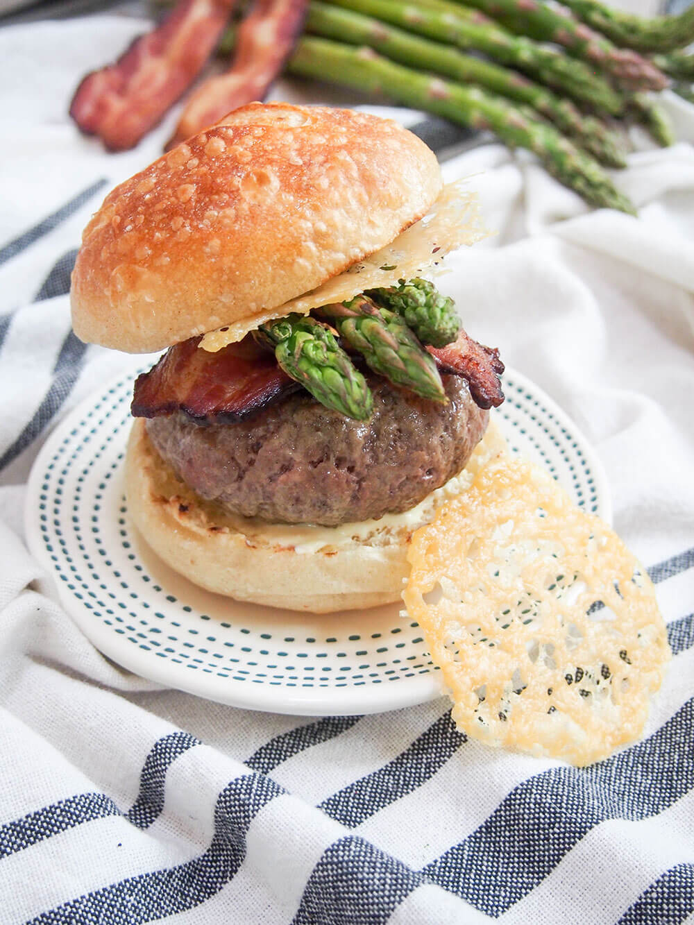 Asparagus parmesan burger with parmesan crisp resting on side of plate
