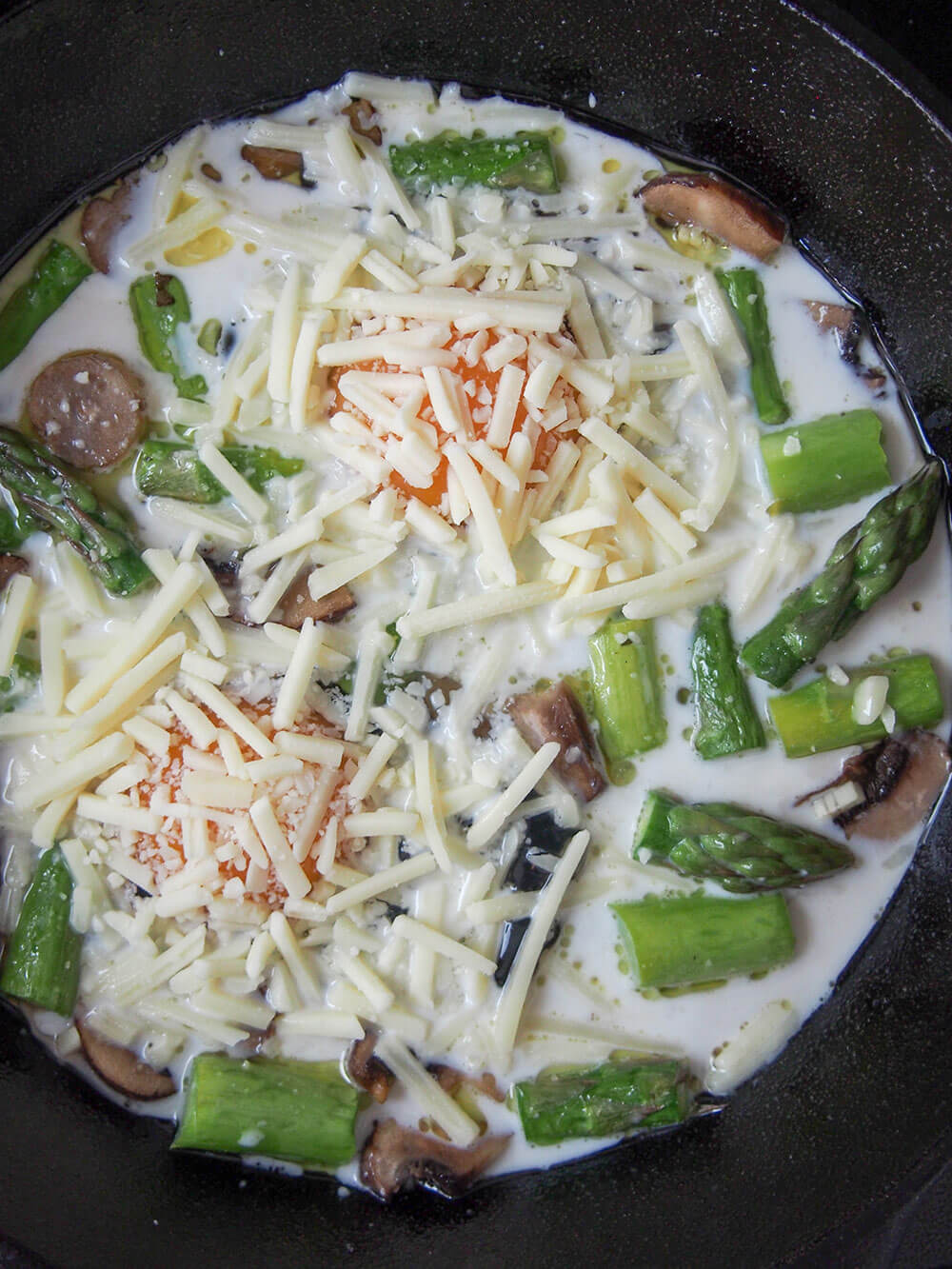 Baked eggs with mushrooms and asparagus ready to bake