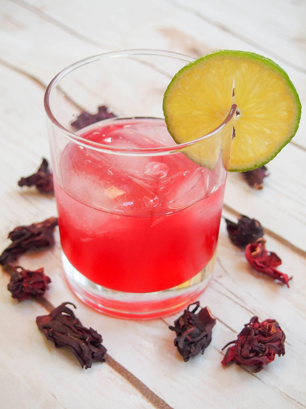 glass of hibiscus mezcal sour with slice of lime as garnish