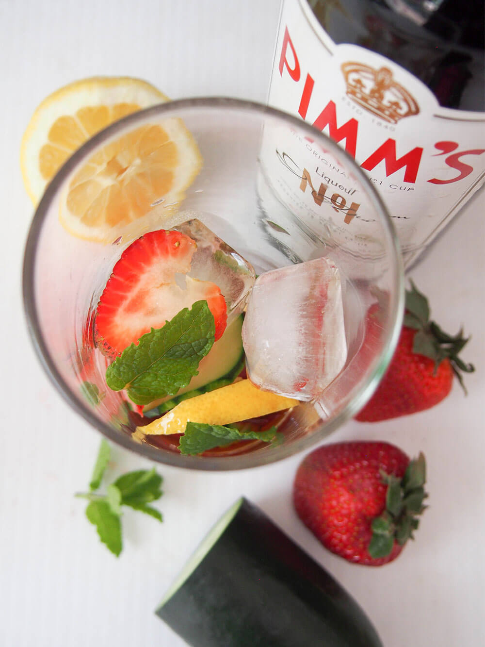 ice, mint and pieces of fruit in glass along with Pimms before topping up