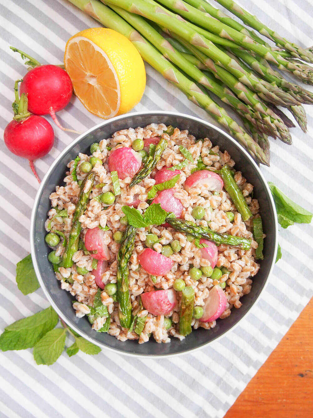 Roasted spring vegetable farro salad with vegetables surrounding bowl