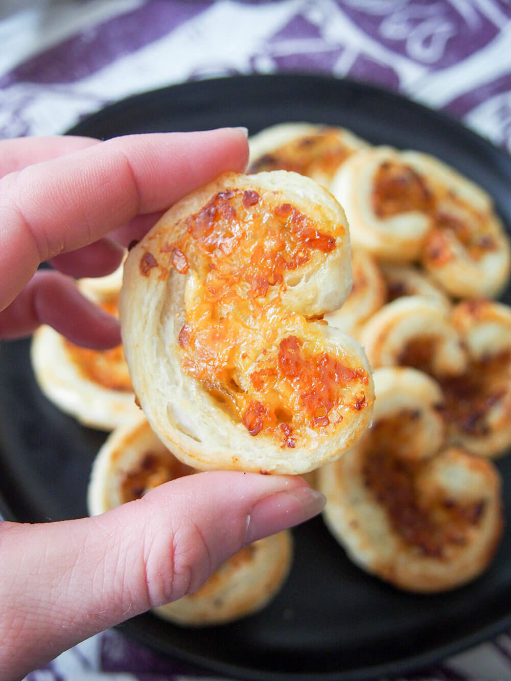 cheese and fig savory palmiers held in hand showing cheesy bottom