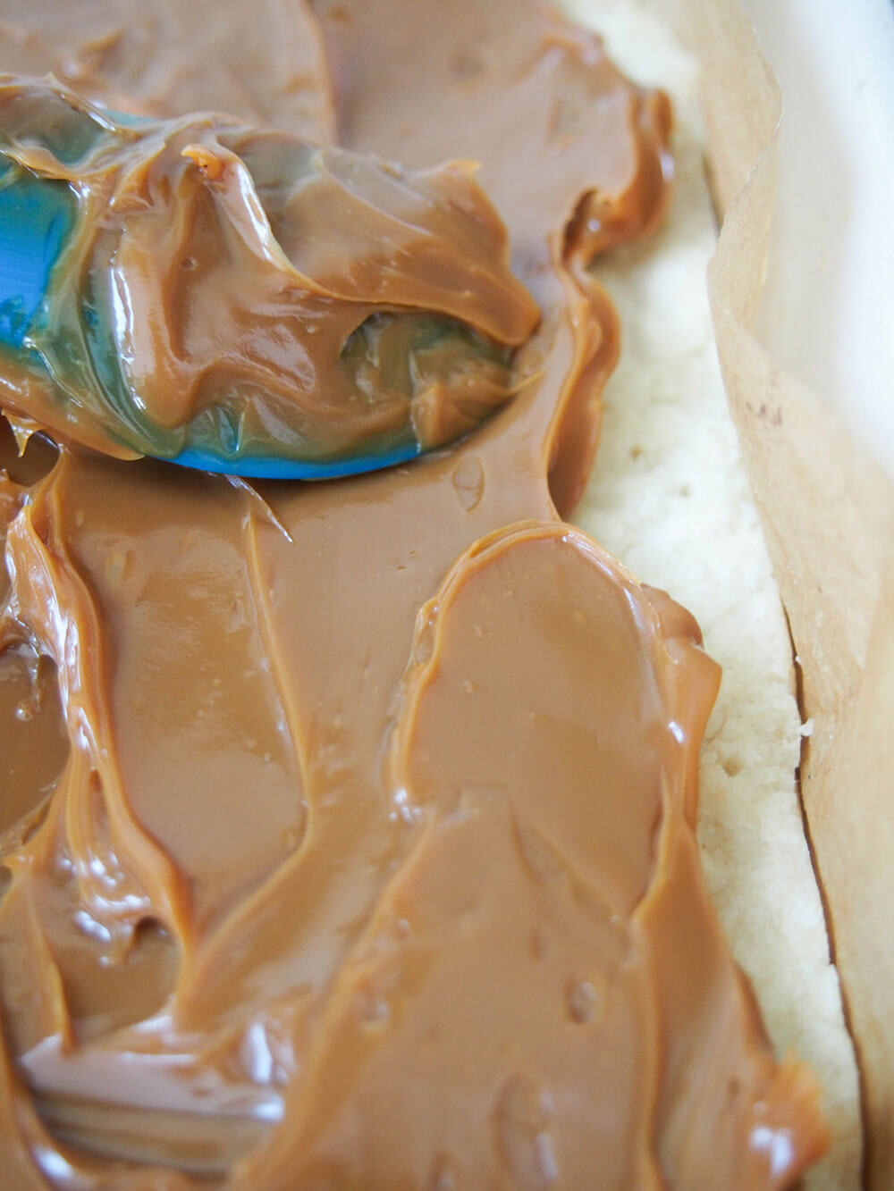 spreading caramel over shortbread base
